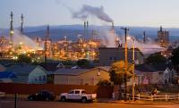 A neighborhood sits in front of an oil refinery. 