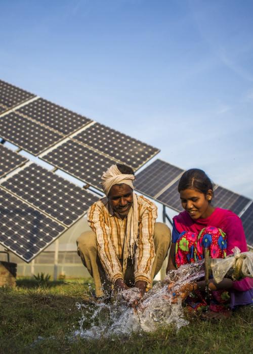 Indian people sitting next to solar panel