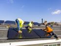 A team of workers install solar panels to a roof in California