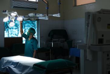 Medical professional turning on lights in hospital room.
