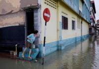 Woman standing door stoop overlooking flooded streets.